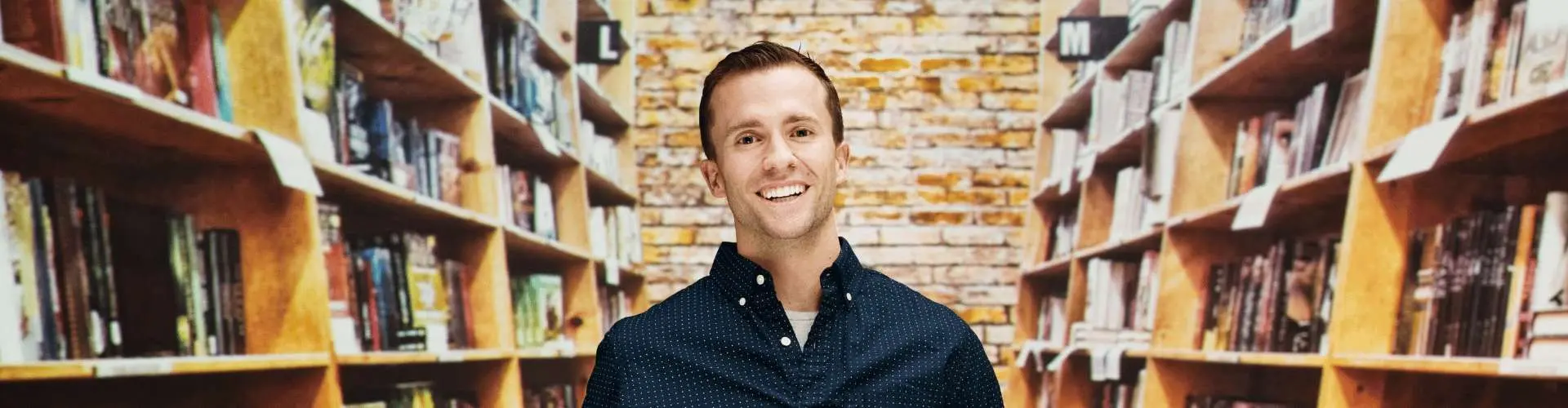 Buchhändler steht in einem Raum mit Bücherregalen