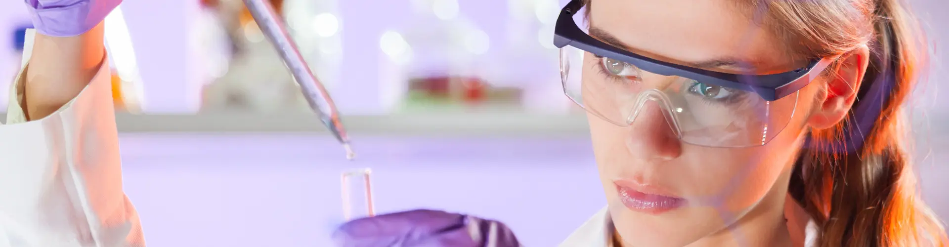 Studentin im dualen Studium Chemie arbeitet im Labor mit Schutzbrille und Pipette