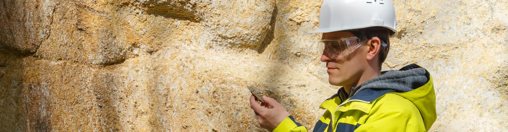 Mann im dualen Studium Geowissenschaften betrachtet einen Stein