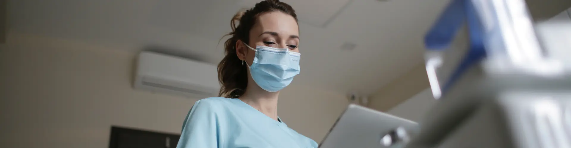 Studentin im dualen Gesundheitsmanagement arbeitet mit Maske am Tablet