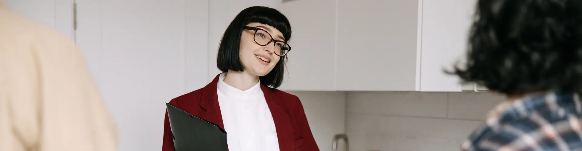 Studentin im dualen Studium Immobilienwirtschaft führt ein Gespräch in einer modernen Wohnung und hält Unterlagen