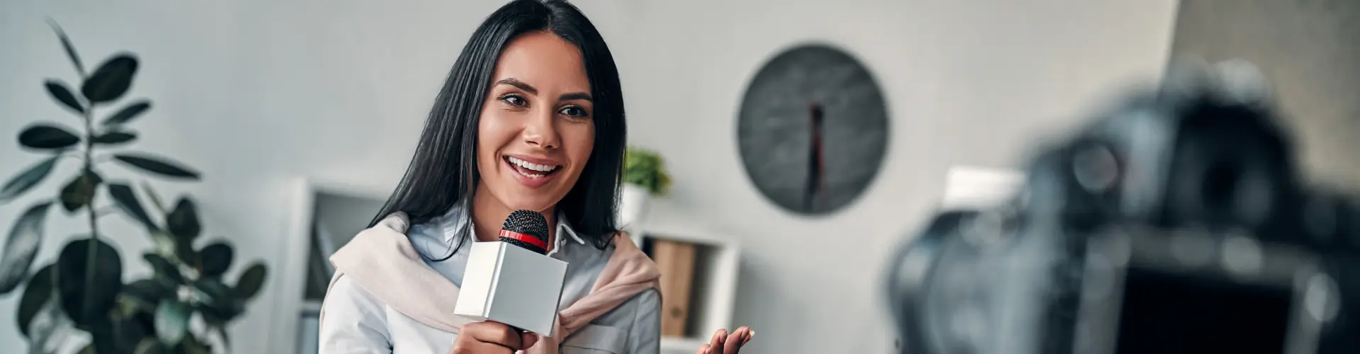 Studentin im dualen Studium Journalismus hält ein Mikrofon vor einer Kamera und führt ein Interview