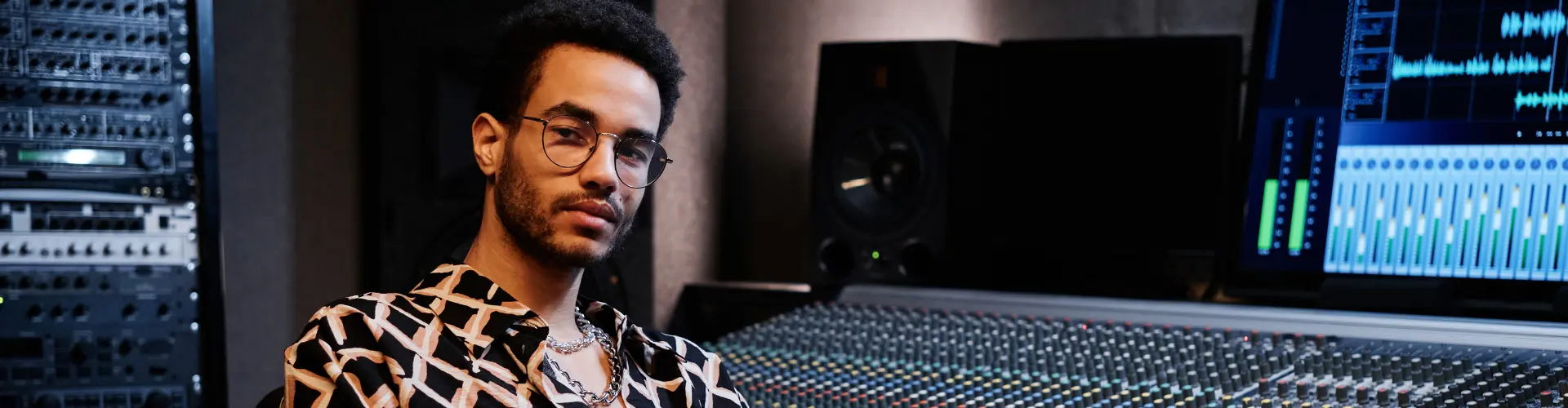 Student im dualen Studium Musikmanagement sitzt im Tonstudio vor einem Mischpult und Audiotechnik