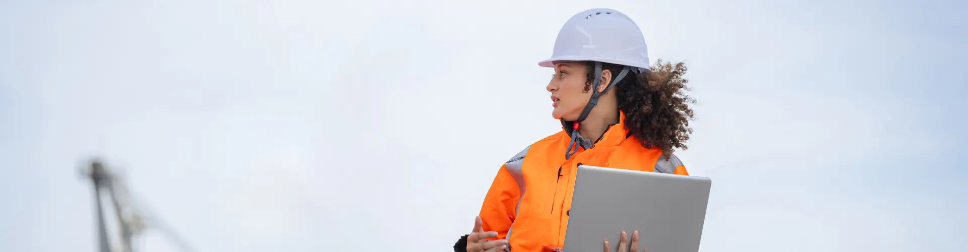 Studentin im dualen Studium Umwelttechnik trägt Schutzhelm und Warnweste und arbeitet mit einem Tablet im Freien