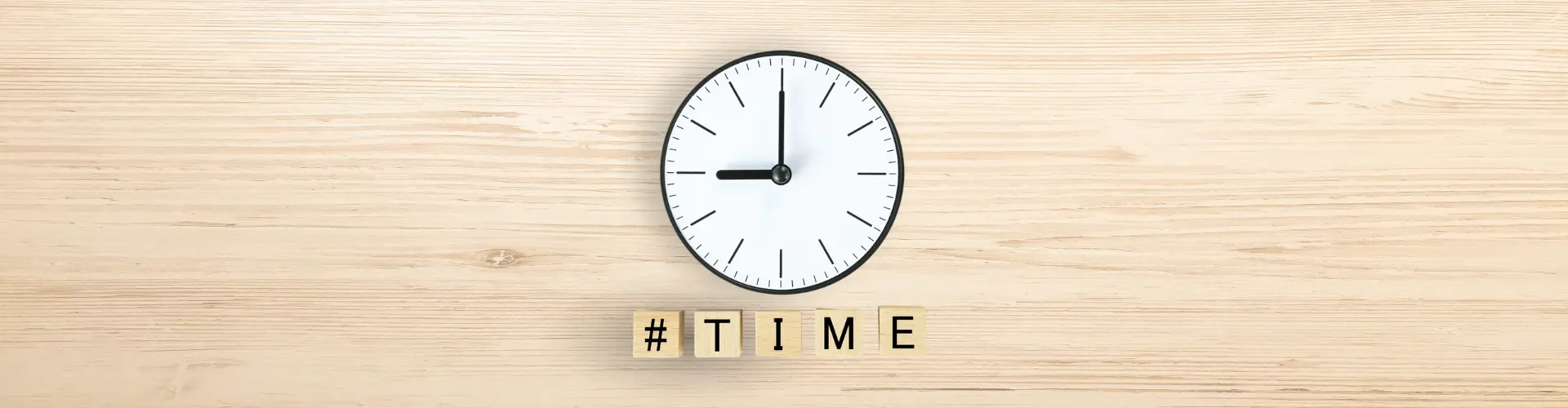 Das Bild zeigt eine Uhr und Holzklötze mit dem Schriftzug TIME – es steht für Zeitmanagement oder das Thema Zeit.