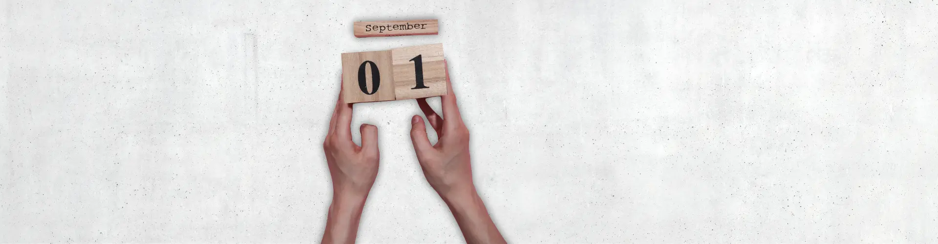 Das Bild zeigt zwei Hände, die Holzklötze mit der Zahl „01“ und dem Schriftzug „September“ halten – es steht für einen Neuanfang oder den Beginn eines Monats.