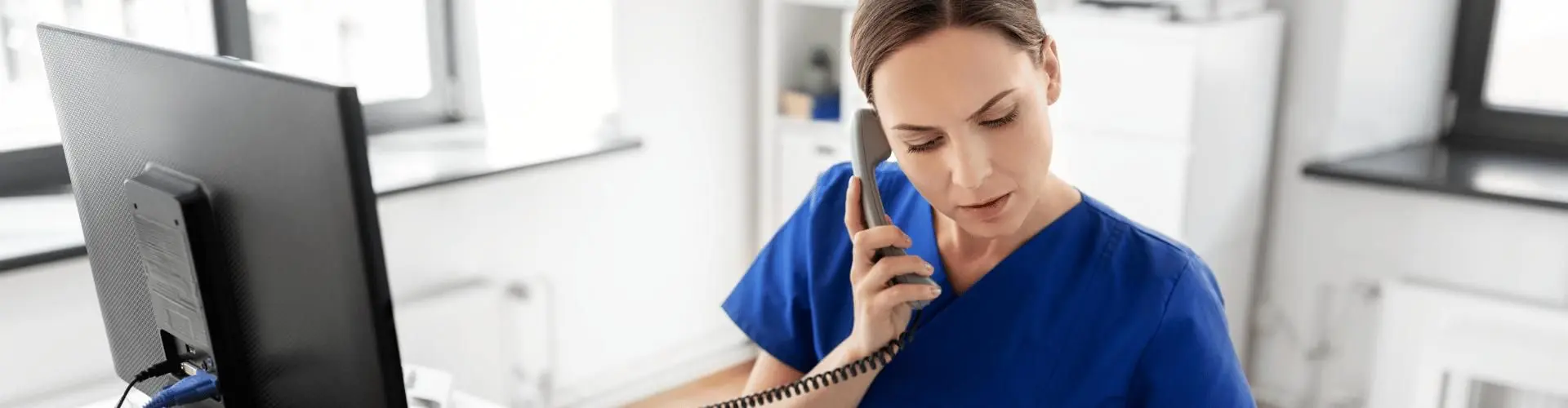 Kauffrau im Gesundheitswesen telefoniert und arbeitet an einem PC