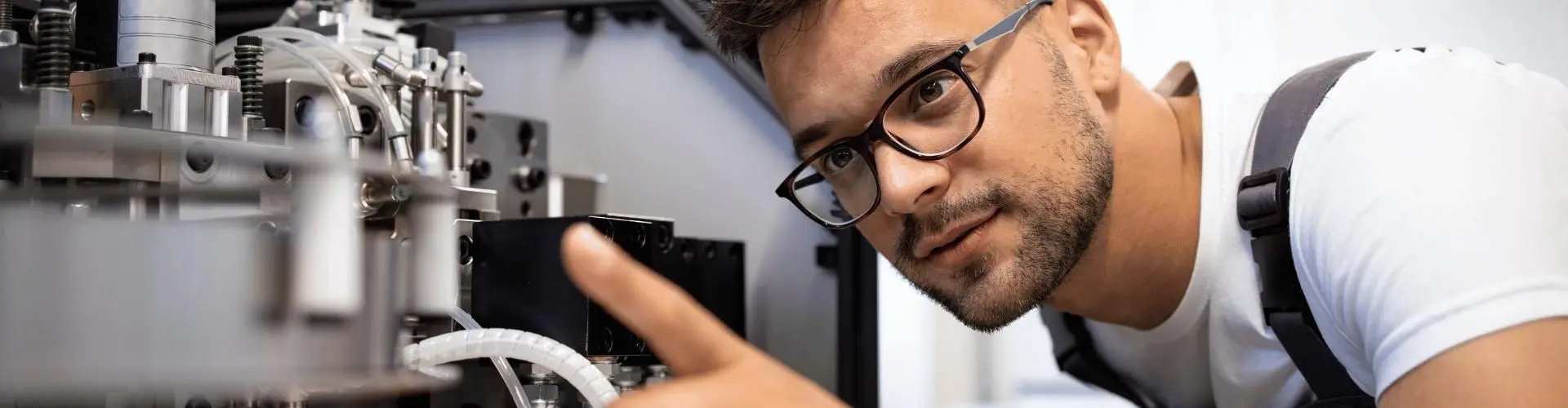 Junger Mann schaut sich Maschine im Detail an