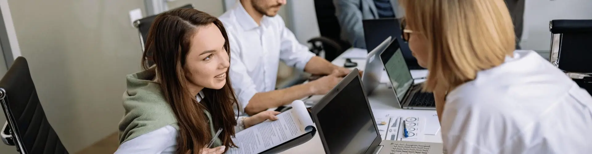 Junge Menschen arbeiten an Laptops und besprechen sich