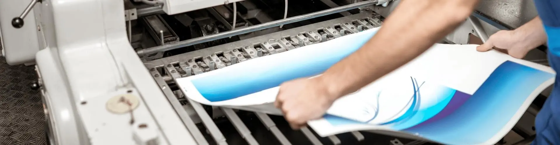 Medientechnologe steht an Druckmaschine und betrachtet Papier