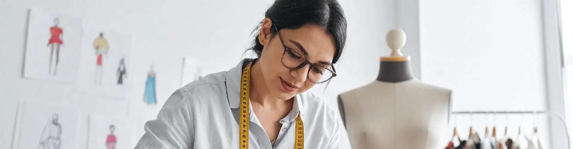 Modedesignerin arbeitet mit einer Modepuppe und einem Maßband