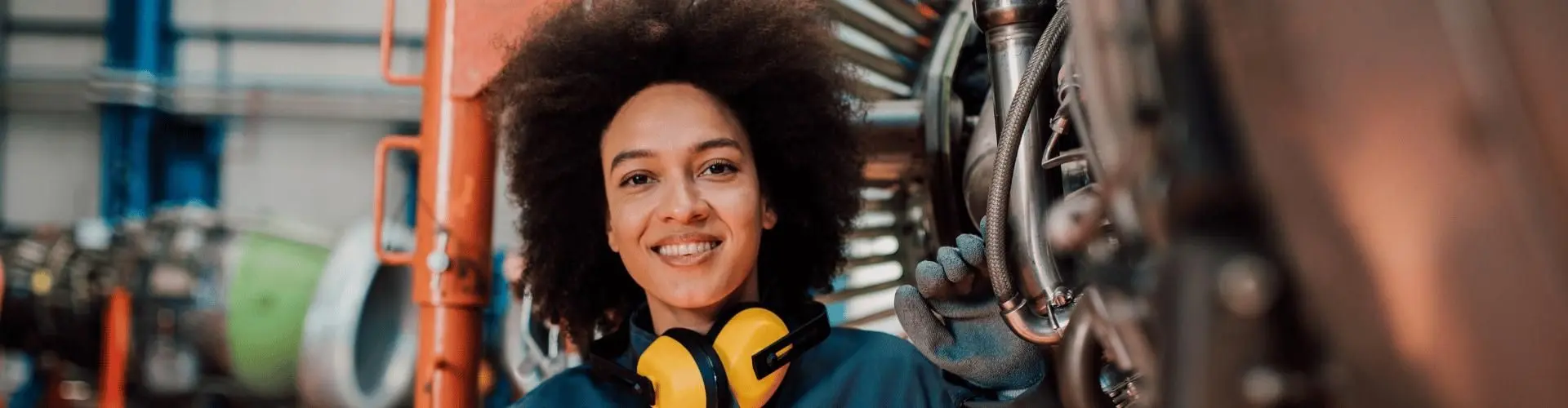 Junge Frau steht vor einer Maschine und lächelt