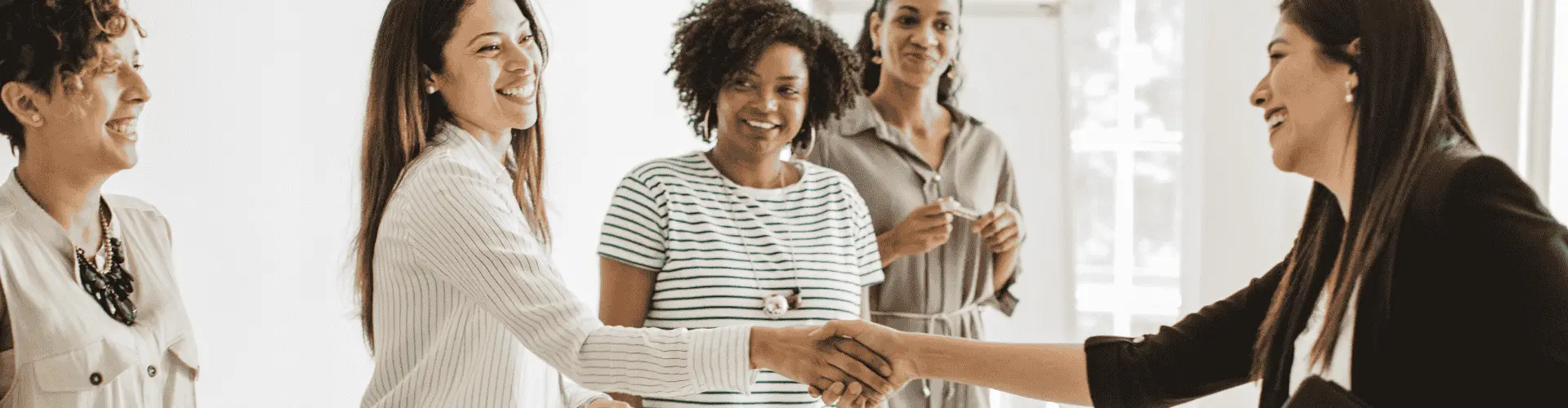 Junge Frauen stehen zusammen und schütteln sich die Hand