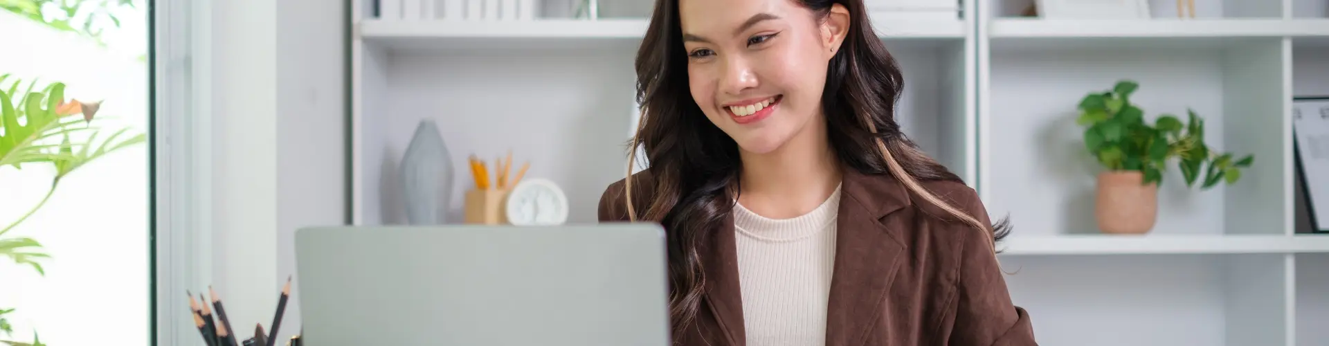 junge Frau sitzt lächelnd vor Laptop