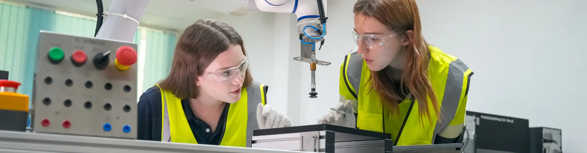 zwei junge Mädchen in Warnwesten hinter einer Maschine