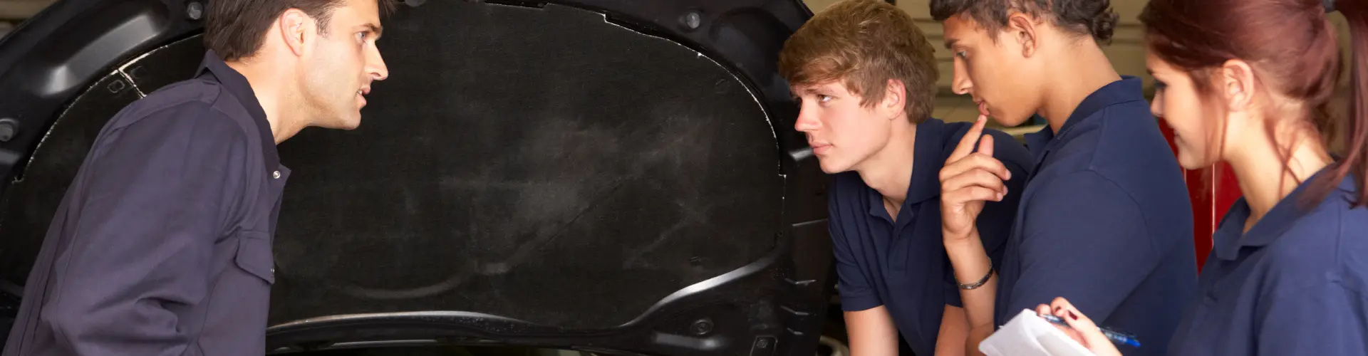 ein Mann zeigt 3 jungen Personen etwas