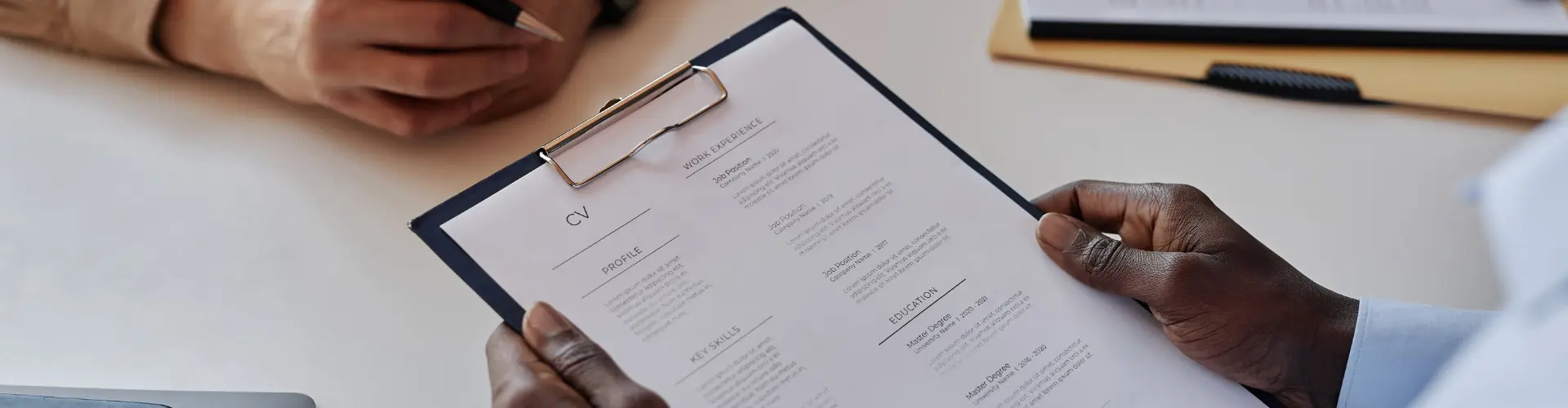 Person hält Klemmbrett mit einem Lebenslauf in der Hand