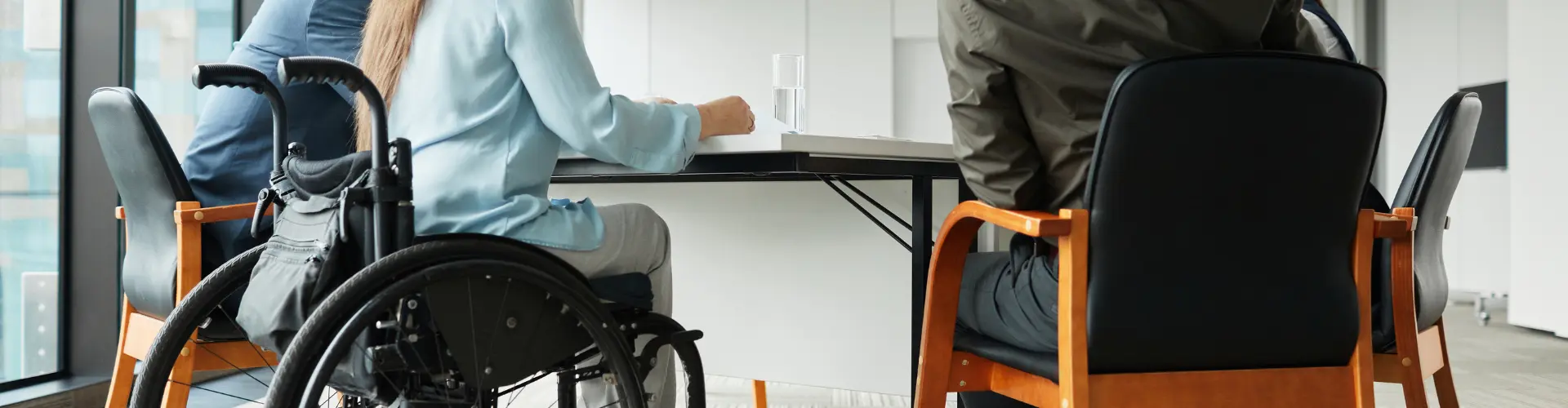 4 Personen davon eine Person im Rollstuhl sitzen an einem Tisch