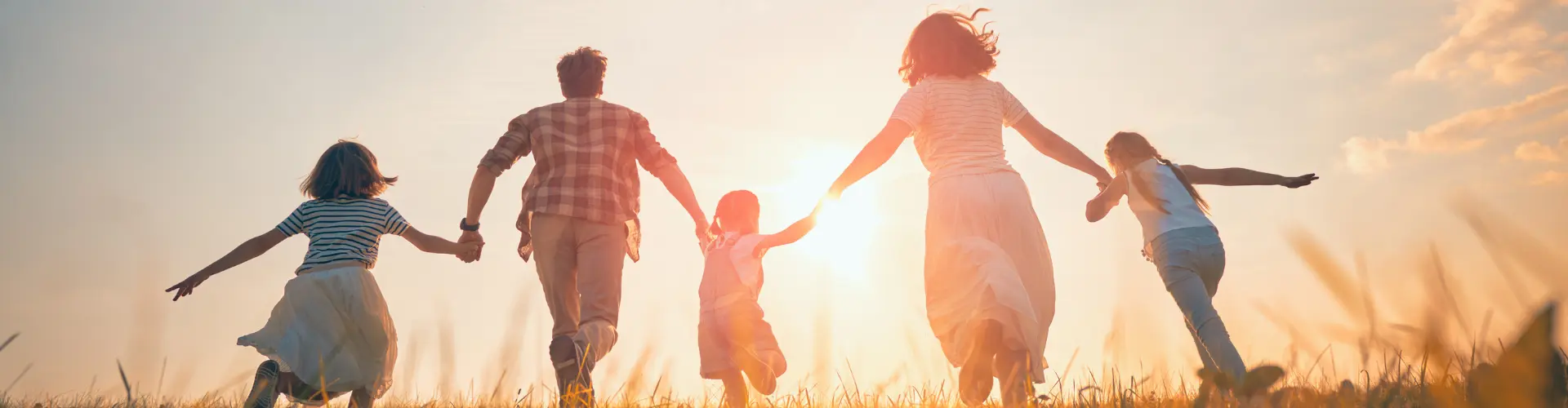 eine Familie die bei Sonnenuntergang im Gras läuft