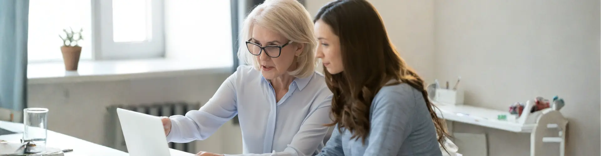 zwei Arbeitskolleginnen arbeiten zusammen vor einem Laptop