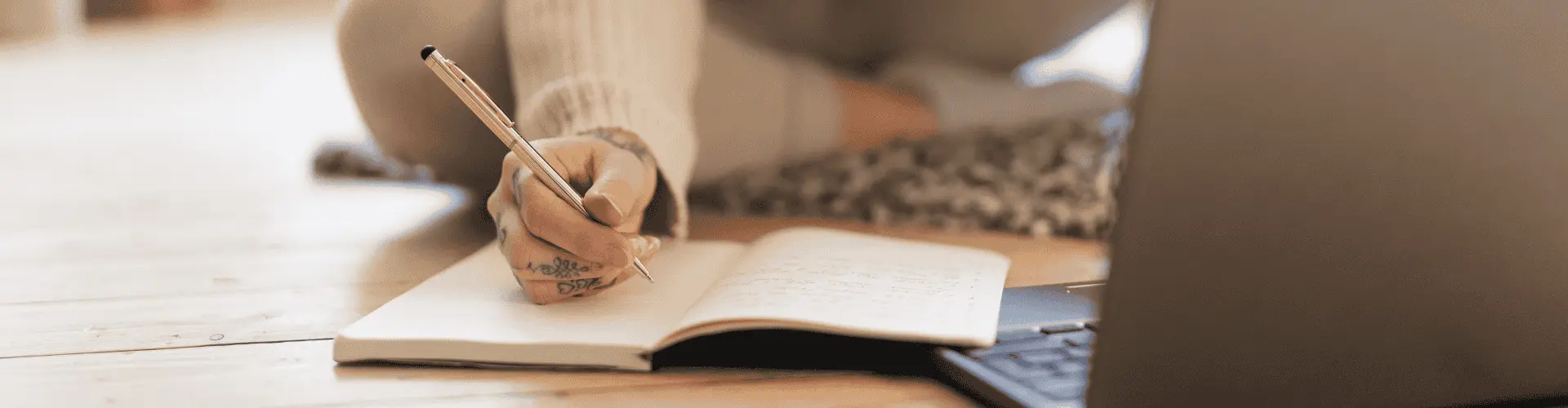 Junge Person recherchiert am Laptop und erstellt Notizen