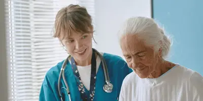 Junge Frau kümmert sich als Altenpflegerin um Patientin