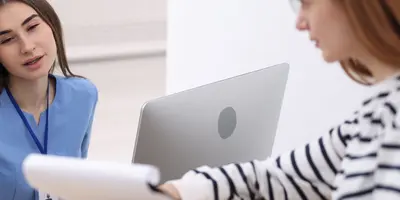 Arzthelferin an der Anmeldung und Patientin