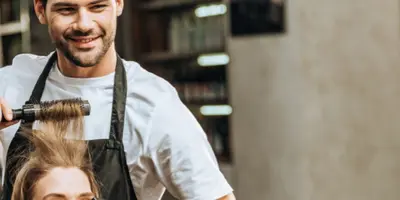 Junger Friseur frisiert Kundin