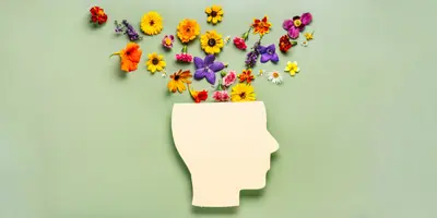 Das Bild zeigt einen Kopf, aus dem bunte Blumen sprießen – es steht für kreative, positive Gedanken.