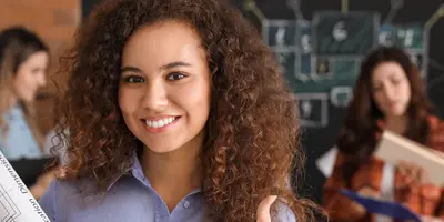Studentin im dualen Architekturstudium hält Baupläne, im Hintergrund steht eine Gruppe