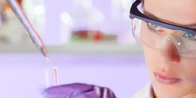 Studentin im dualen Studium Chemie arbeitet im Labor mit Schutzbrille und Pipette