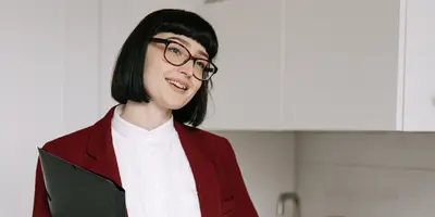 Studentin im dualen Studium Immobilienwirtschaft führt ein Gespräch in einer modernen Wohnung und hält Unterlagen