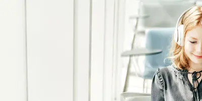 Studentin im dualen Studium Medienmanagement trägt Kopfhörer in einem modernen Raum