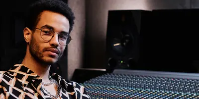 Student im dualen Studium Musikmanagement sitzt im Tonstudio vor einem Mischpult und Audiotechnik