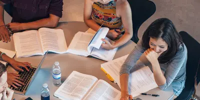 Das Bild zeigt eine Lerngruppe mit geöffneten Büchern, Laptop und Wasserflaschen – es steht für Studium, gemeinsames Lernen und die Vereinbarkeit von Familie und Ausbildung.