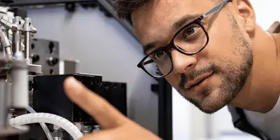 Junger Mann schaut sich Maschine im Detail an