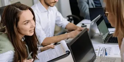 Junge Menschen arbeiten an Laptops und besprechen sich