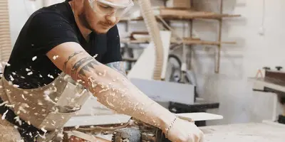 Junger Tischler arbeitet in einer Werkstatt mit Holz