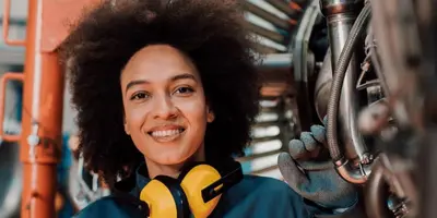 Junge Frau steht vor einer Maschine und lächelt