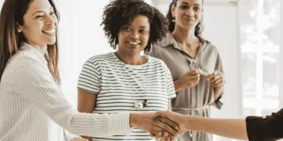 Junge Frauen stehen zusammen und schütteln sich die Hand