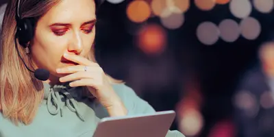 junge Frau mit Headset schaut konzentriert auf Tablet