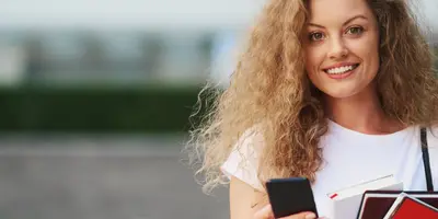 Junge Frau mit Handy und Büchern in der Hand