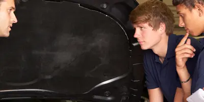 ein Mann zeigt 3 jungen Personen etwas