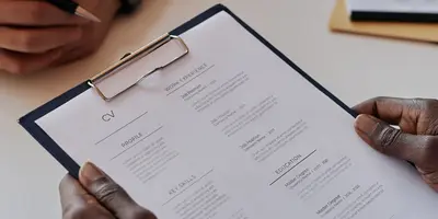 Person hält Klemmbrett mit einem Lebenslauf in der Hand