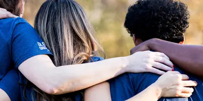 Junge Menschen stehen in einer Reihe zusammen und haben sich im Arm