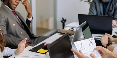 junge Personen sitzen zusammen am Tisch und besprechen sich