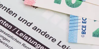 Rentenbescheid, über dem einige Euro‑Scheine liegen