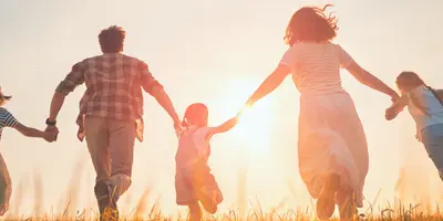 eine Familie die bei Sonnenuntergang im Gras läuft