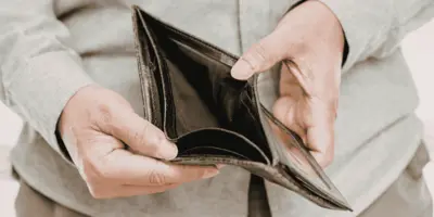 Mann zeigt einen leeren Geldbeutel