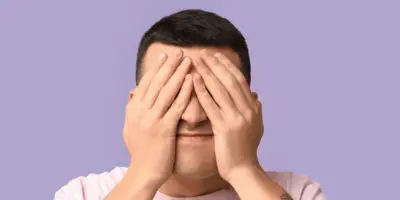 Junger Mann hält sich die Hände vor das Gesicht